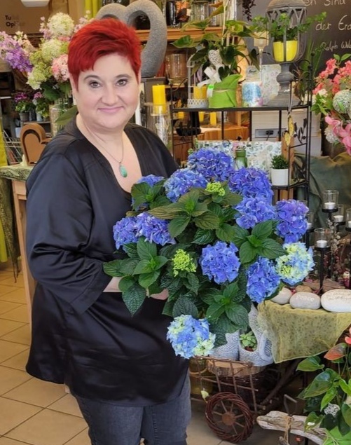 Inhaberin Sonja Kepplinger mit blauen Blumen